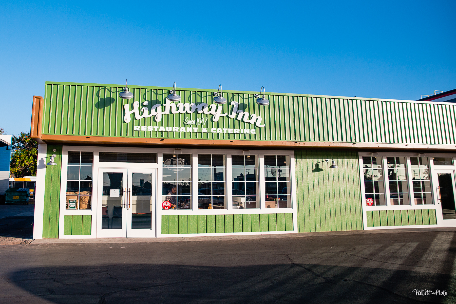 Highway Inn Restaurant in Waiaphu from the front entrance, a green building with white trim against a blue sky.